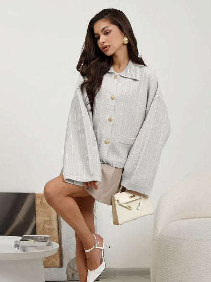 Chic model showcasing the Glacier Cardigan by Lauven in light gray oversized knitwear with bell sleeves.