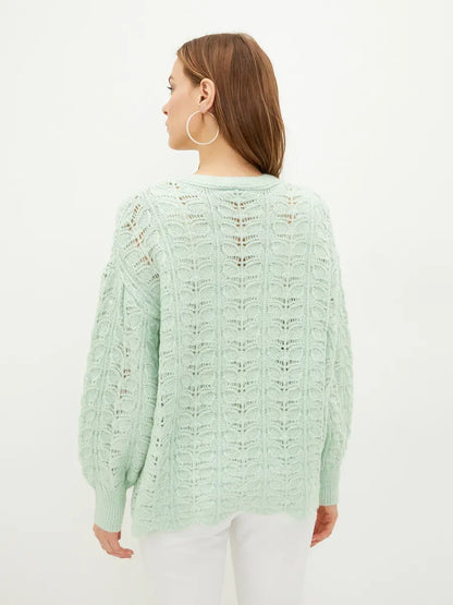 Back view of a woman wearing the Celestia Cardigan by Lauven in soft green with a delicate knit design.