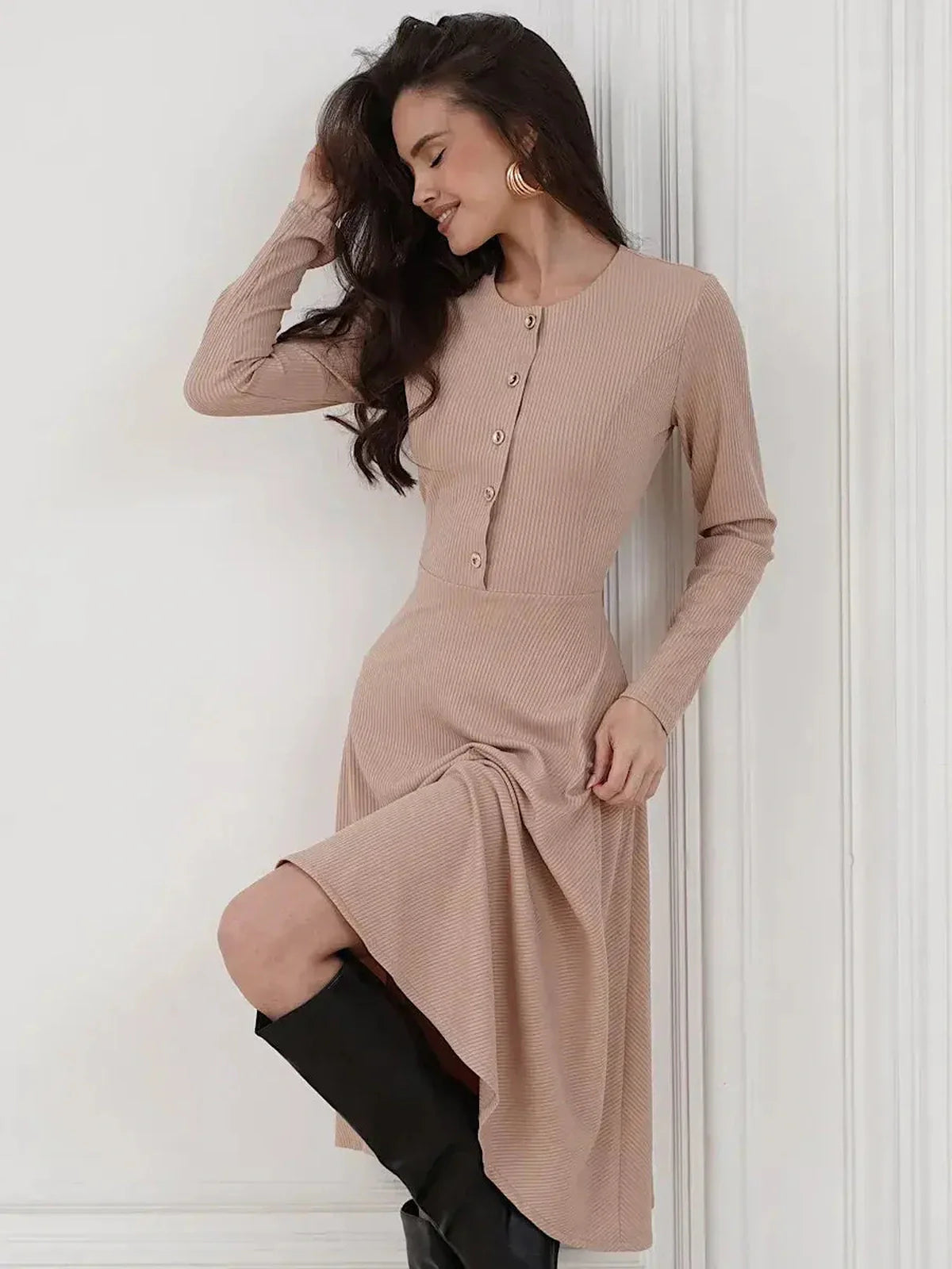 Woman in ribbed beige midi dress with button accents, showcasing a stylish and elegant silhouette.