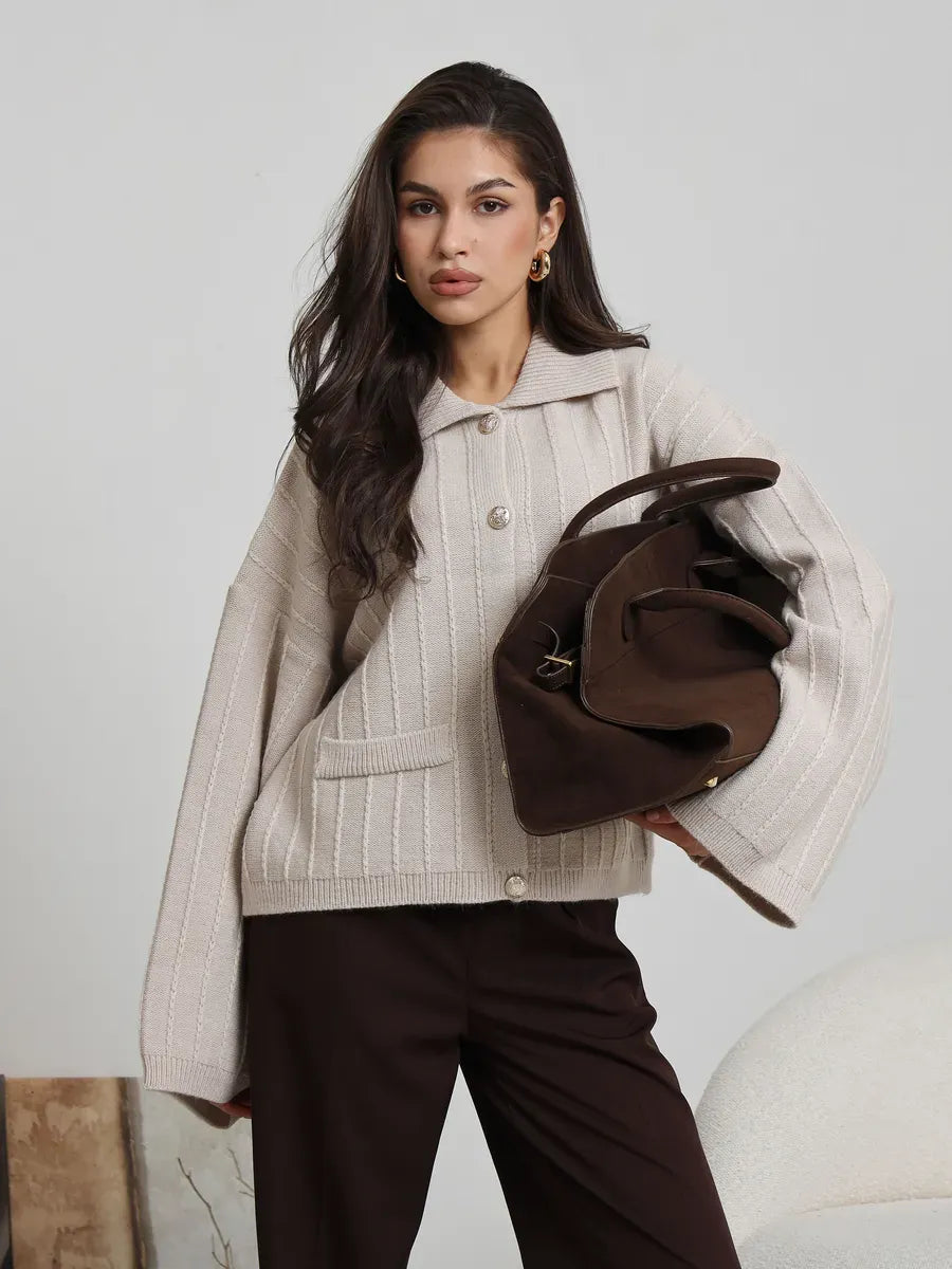 Lauven Dune Cardigan in soft light beige with oversized silhouette and bell sleeves, paired with a brown handbag.