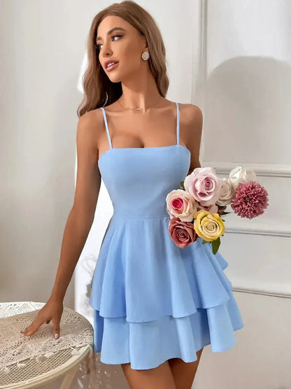 Model showcasing the Sky Petal Mini Dress in light blue, featuring a tiered skirt and holding a bouquet of flowers.