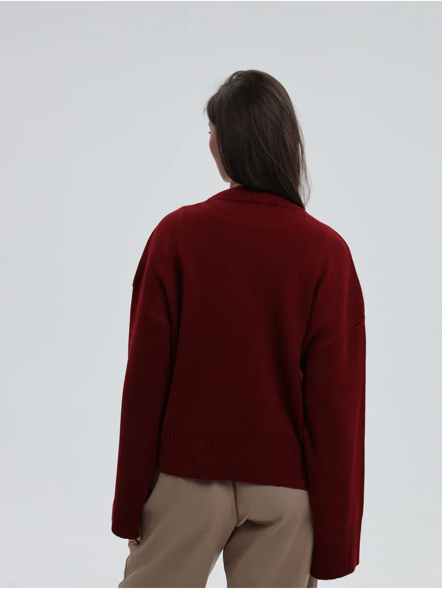 Back view of a woman wearing the Valora Sweater in burgundy red by Lauven, showcasing its oversized knit design.