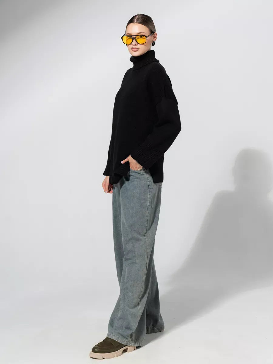 Model wearing an oversized Onyx Sweater by Lauven in black, paired with wide-leg jeans and sunglasses.