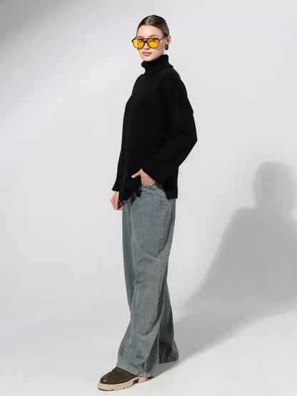 Model wearing an oversized Onyx Sweater by Lauven in black, paired with wide-leg jeans and sunglasses.