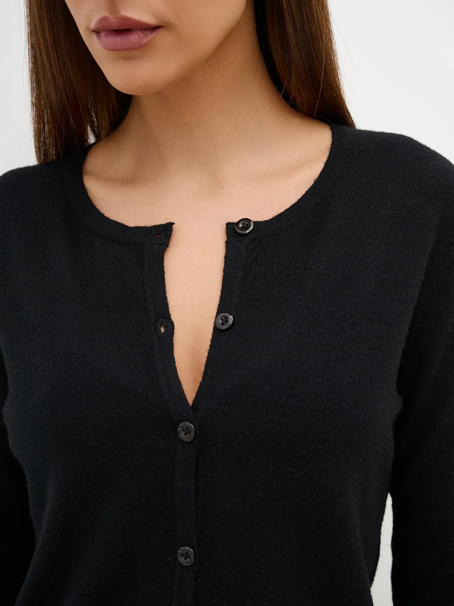 Close-up of a model wearing the Lauven Orion Cardigan, showcasing button closure and soft black knit fabric.