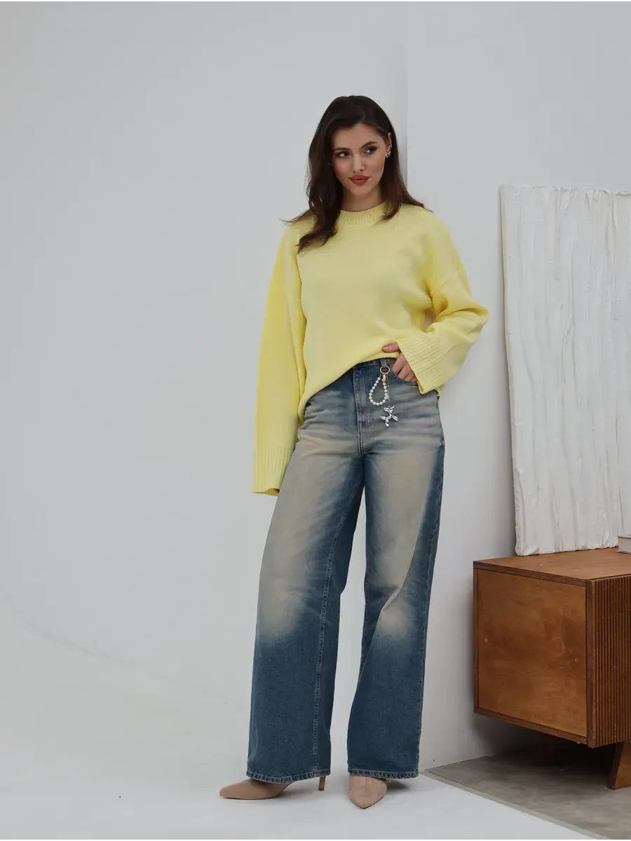 Model wearing Solara Sweater by Lauven, a light yellow oversized knit, styled with wide-leg jeans.