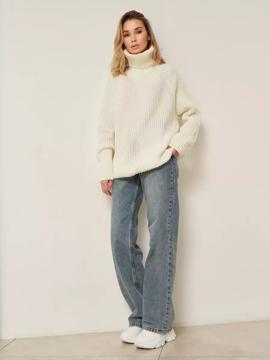 Model wearing the Luna Sweater by Lauven, a cozy oversized white knit turtleneck paired with blue jeans.