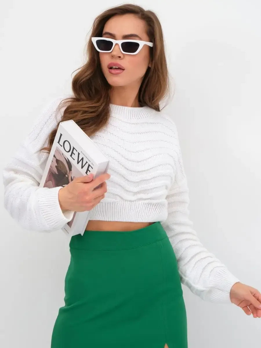 Woman wearing the Lyra Sweater by Lauven, a white cropped knit with relaxed fit, styled with a green skirt.
