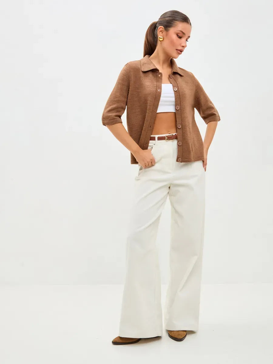 Model showcasing Marin Cardigan by Lauven, lightweight brown wool blend knitwear paired with white trousers.