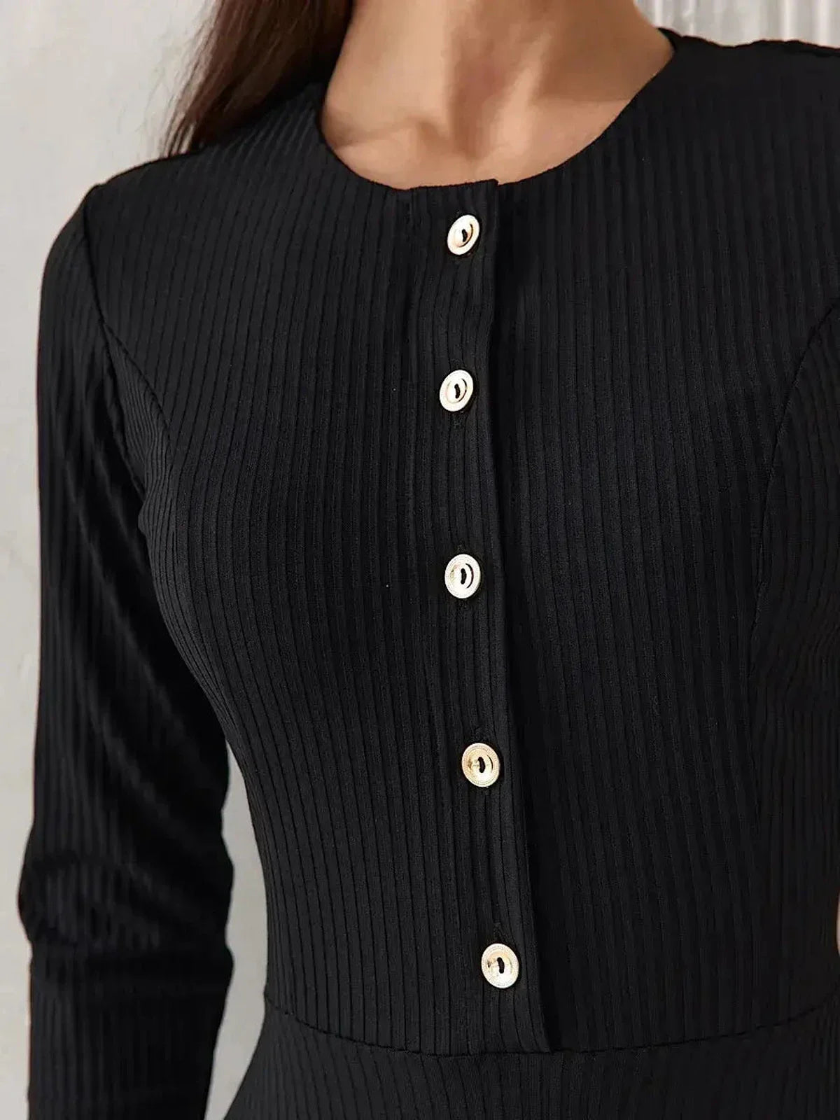 Close-up of the Serene Grace Midi Dress showcasing its black ribbed fabric and decorative buttons, highlighting elegant sophistication.
