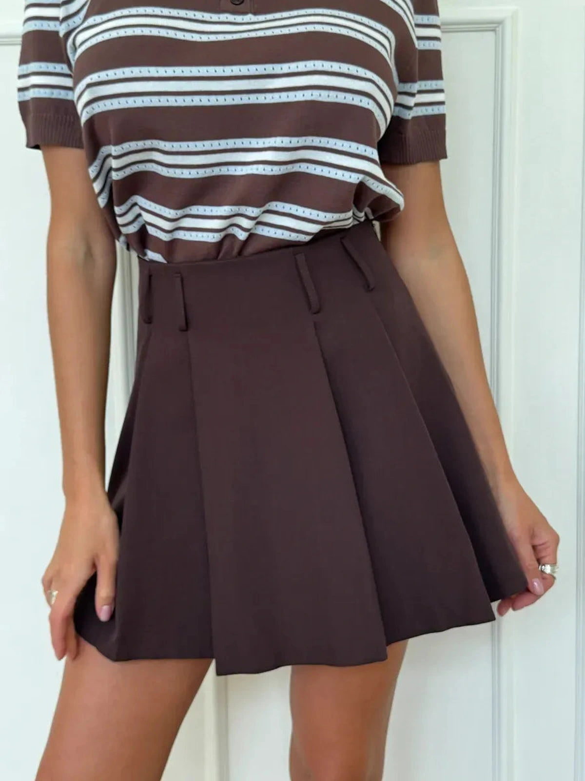 Verona Mini Skirt by Lauven in chocolate brown, showcasing a pleated A-line design with a mid-rise fit.