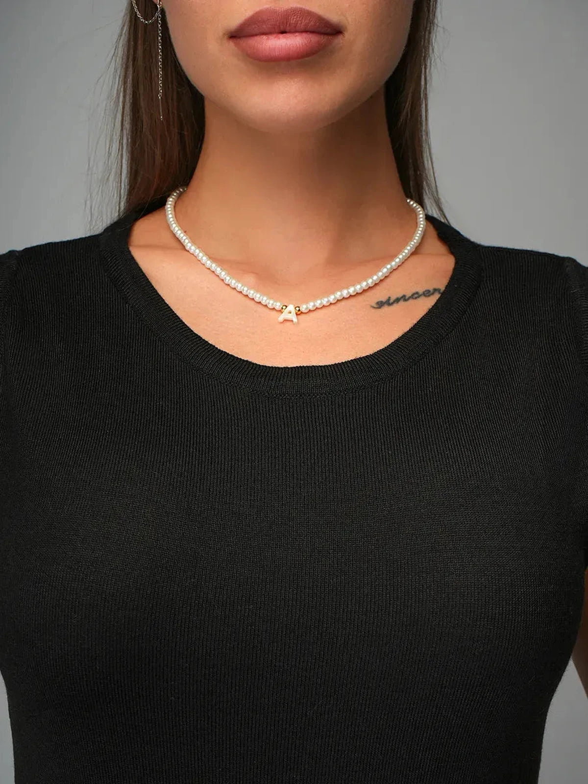 Close-up of woman wearing pearl necklace and black knit top, showcasing elegant style with the Velora Midi Dress.