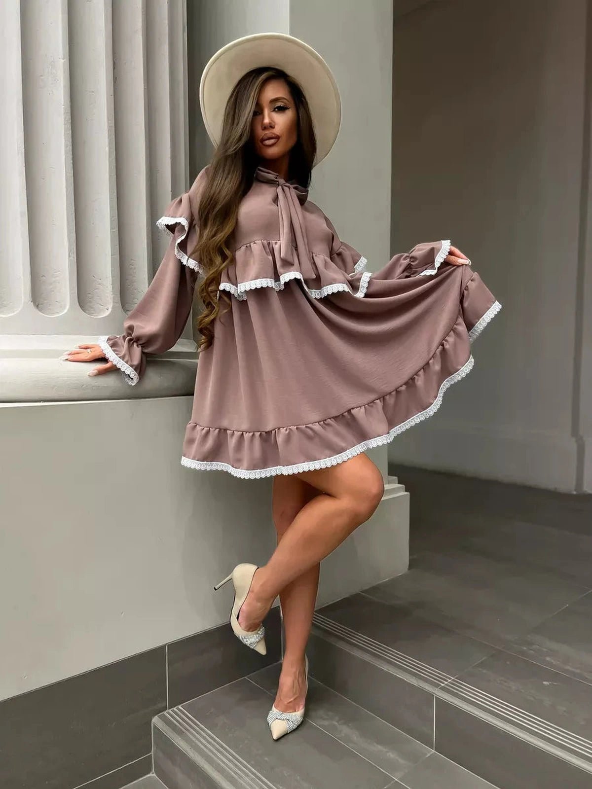 Aurora Mini Dress by Lauven, featuring soft ruffles and lace trim, styled elegantly with a wide-brim hat.