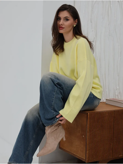 Woman wearing Solara Sweater by Lauven in light yellow, styled with blue jeans on a wooden surface.