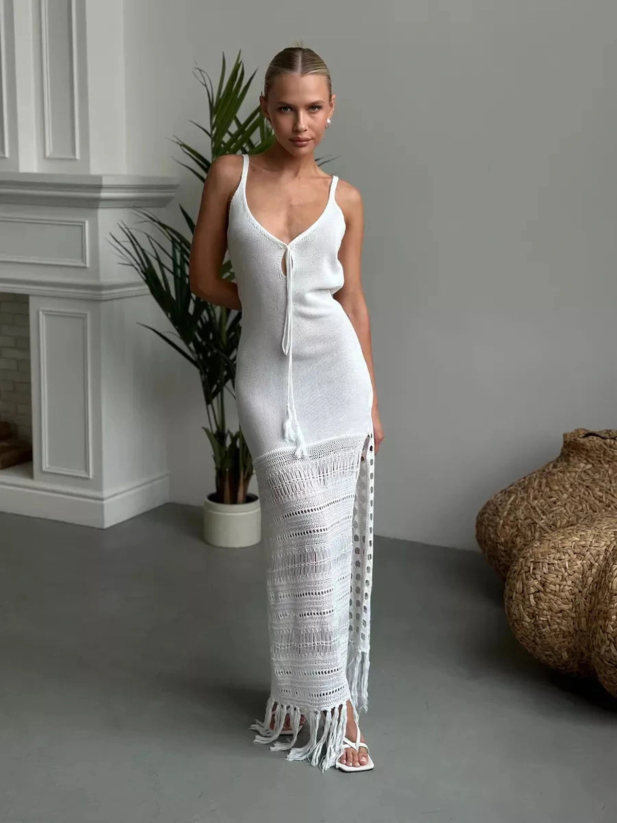 Elegant woman wearing the Solara Maxi Dress by Lauven featuring airy knit, side slit, and fringe hem.