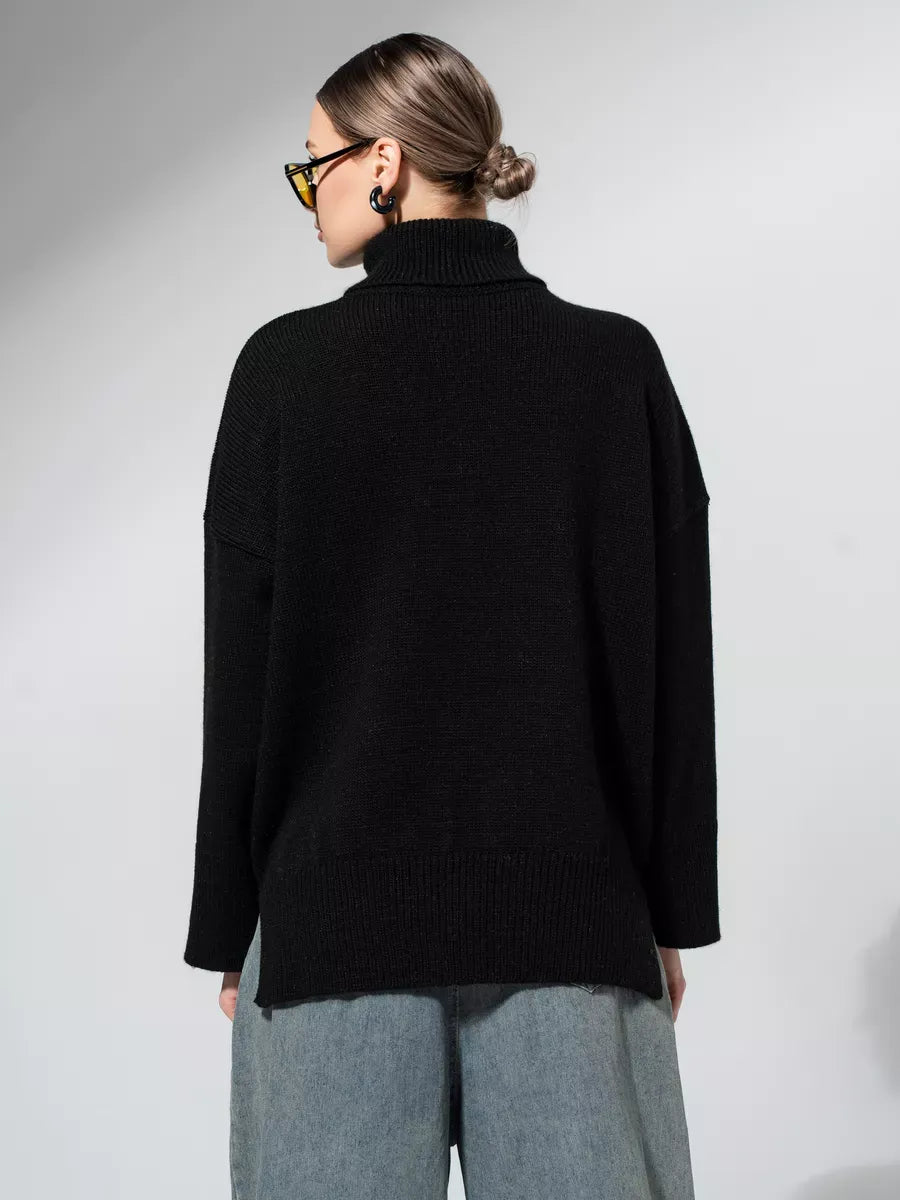 Back view of a woman wearing the Onyx Sweater by Lauven, showcasing its oversized knit design in classic black.