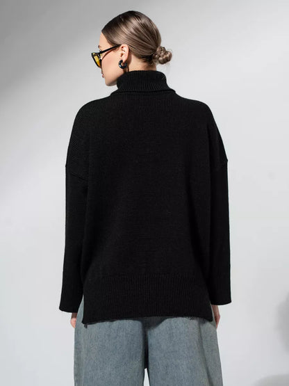 Back view of a woman wearing the Onyx Sweater by Lauven, showcasing its oversized knit design in classic black.