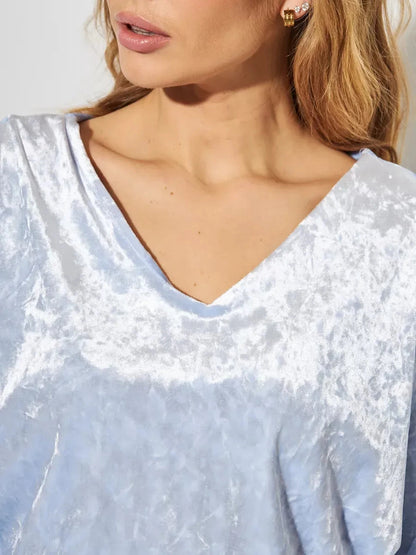 Close-up of a woman in a light blue velvet top showcasing the V-neckline, part of the Lunara Maxi Dress by Lauven.