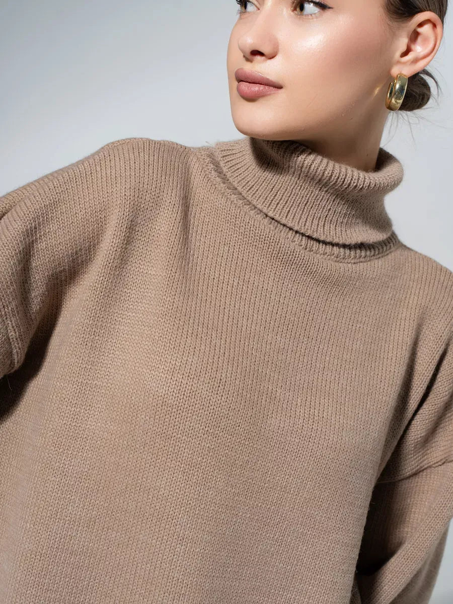 Woman wearing a cozy Capri Sweater in warm cappuccino, showcasing its oversized knit and turtleneck collar by Lauven.