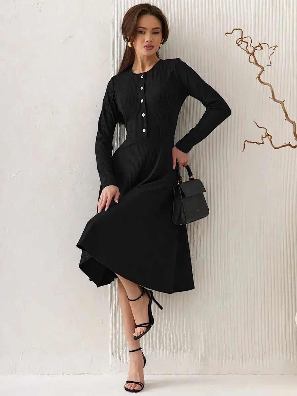 Model wearing the Serene Grace Midi Dress, a black ribbed midi dress with button details and a flared skirt.