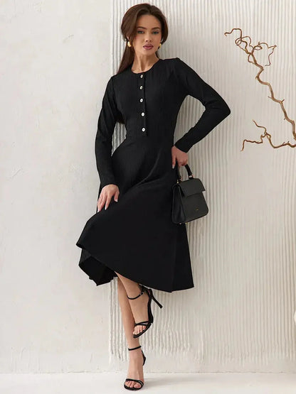Model wearing the Serene Grace Midi Dress, a black ribbed midi dress with button details and a flared skirt.