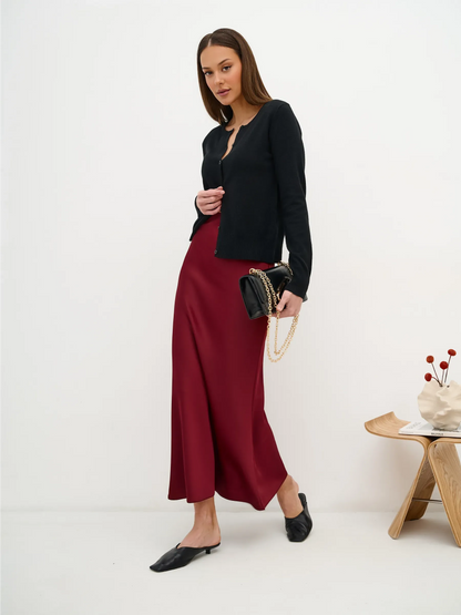 Model wearing Orion Cardigan by Lauven with a burgundy skirt, showcasing sleek black knitwear and stylish accessories.