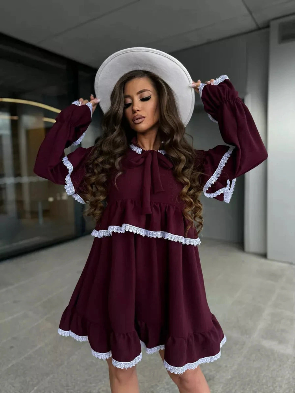 Model wearing the Marina Mini Dress by Lauven, featuring ruffles and lace details in rich burgundy color.