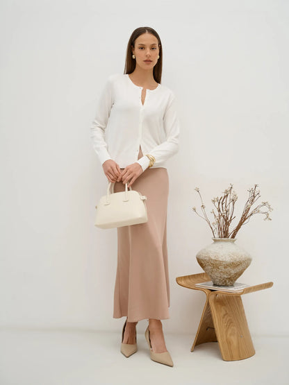 Selene Cardigan by Lauven, an elegant white knitwear piece styled with a beige skirt and handbag.