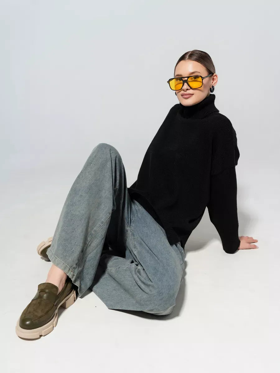 Onyx Sweater by Lauven, oversized knit in classic black, styled with gray pants and yellow sunglasses.