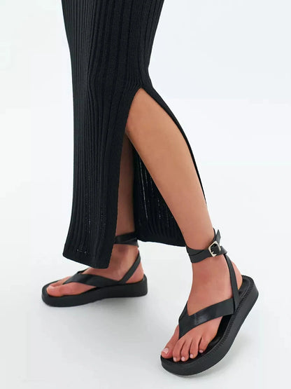 Close-up of leg showcasing black ribbed Noir Midi Dress by Lauven with stylish sandals.