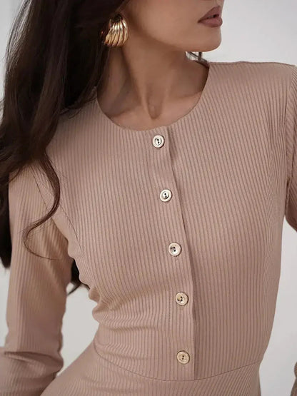Detail of a model wearing the Sculpted Ease Midi Dress in ribbed beige, featuring gold-tone buttons and a round neckline.