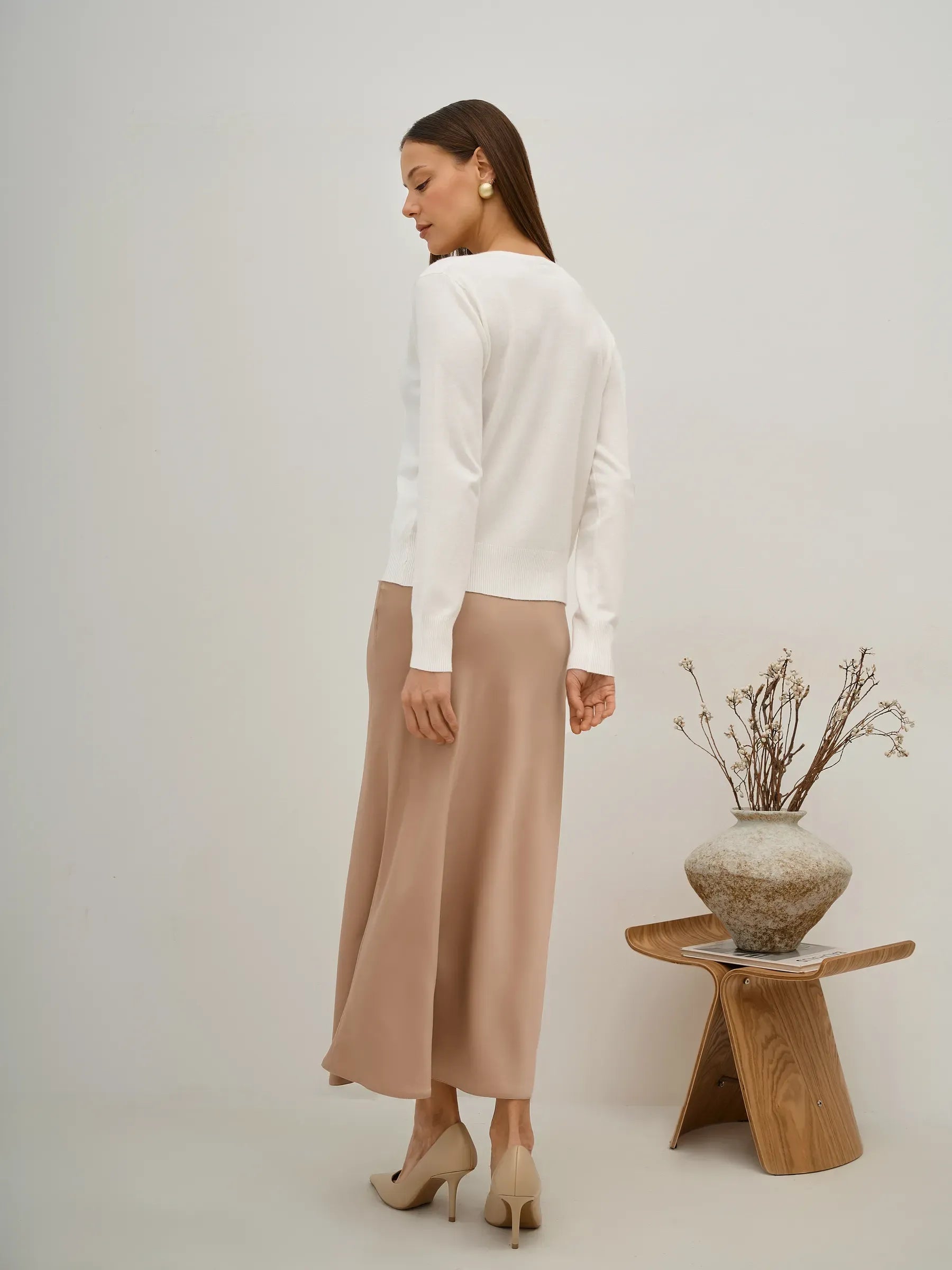 Model wearing Selene Cardigan by Lauven, elegant white knitwear paired with a flowing beige skirt.
