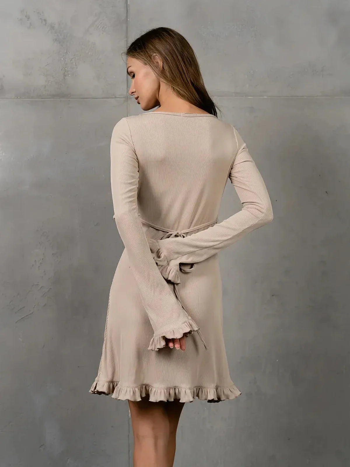 Back view of Luna Flare beige long sleeve dress featuring ruffle accents and adjustable lace-up details.