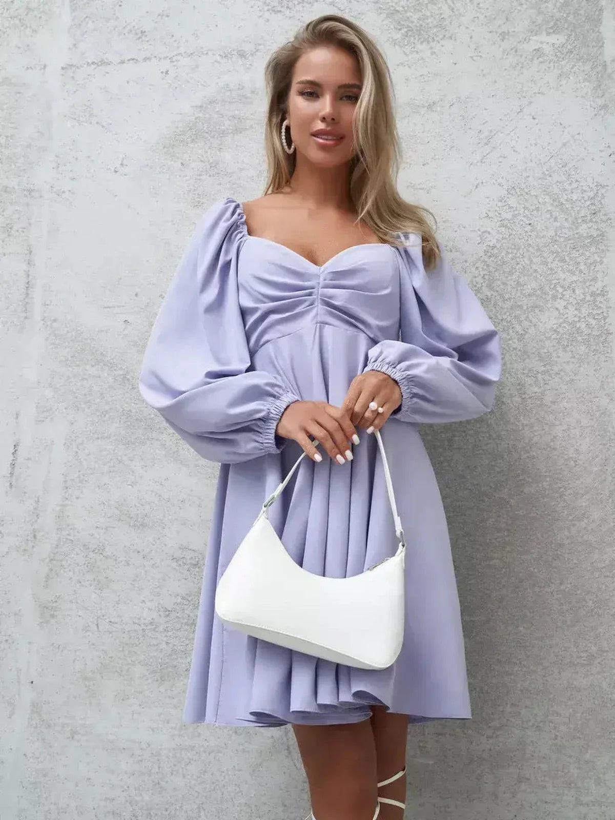 Elegant lilac mini dress with voluminous sleeves, featuring a V-neckline and a white handbag.