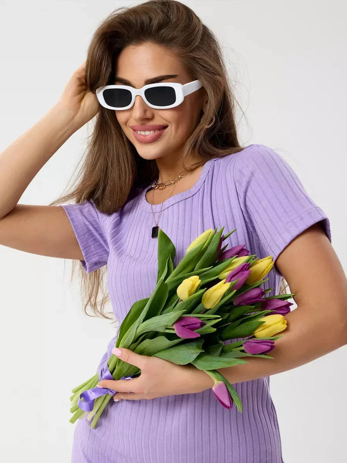 Woman in a lilac ripple mini dress holding a bouquet of tulips, wearing stylish white sunglasses in a bright, cheerful setting.