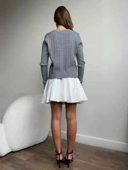 Rear view of a model wearing a Sterling Cardigan by Lauven, showcasing its lightweight grey cable knit design.