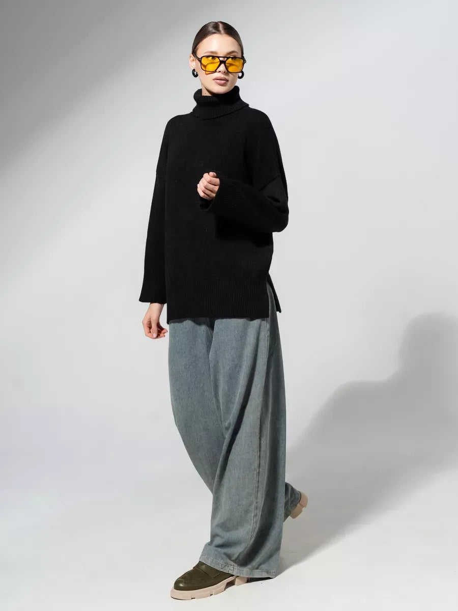 Model wearing the Onyx Sweater by Lauven in classic black, styled with wide jeans and bold sunglasses.