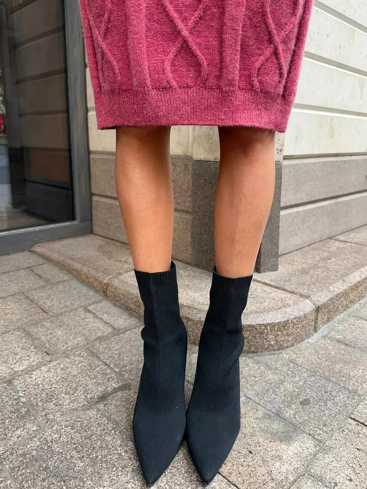 Close-up of legs wearing black sock heels paired with a stylish berry midi dress.