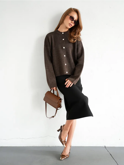 Model showcasing Cocoa Cardigan by Lauven, featuring warm brown knitwear with button closure, paired with a chic skirt.