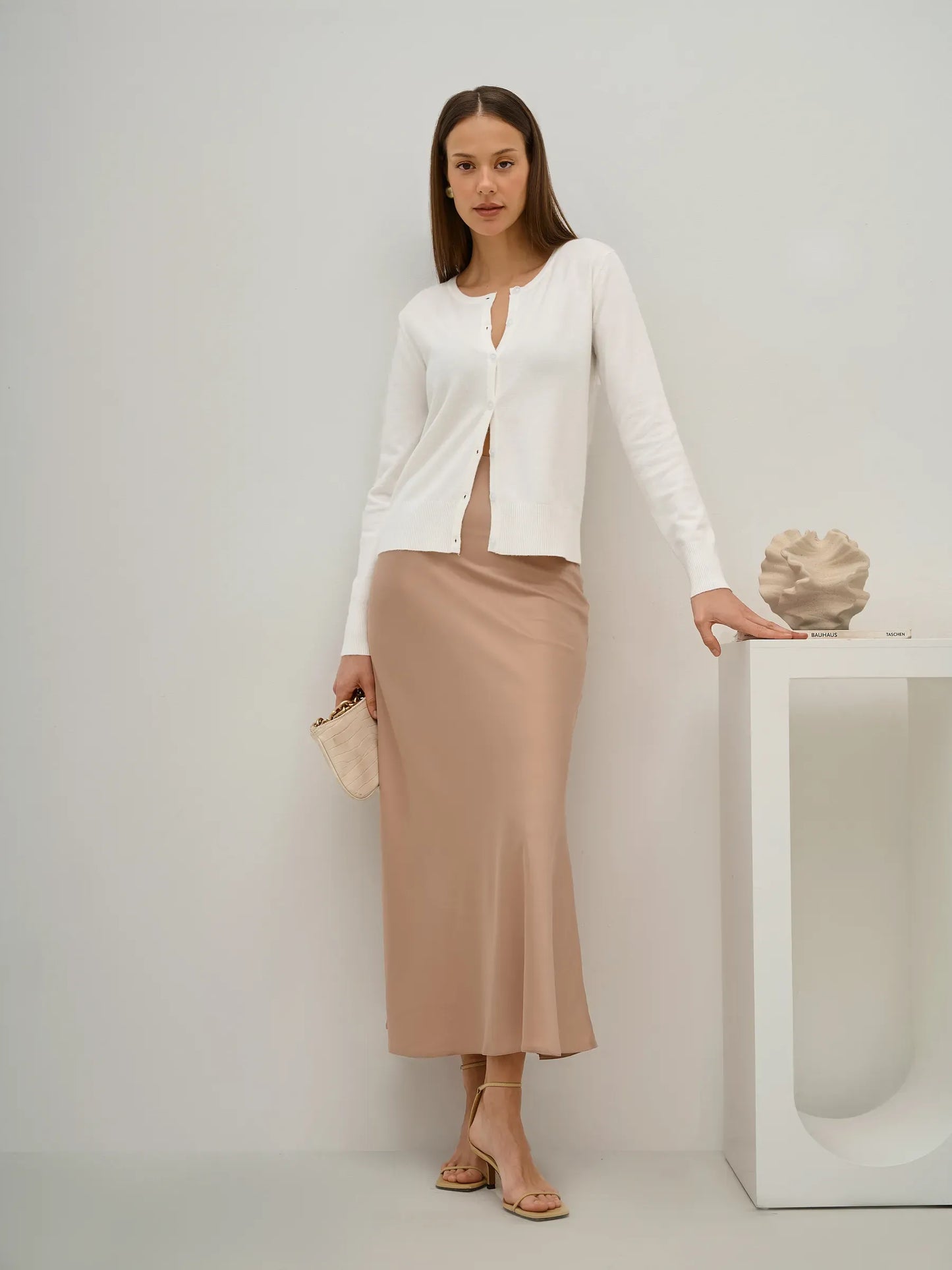 Selene Cardigan by Lauven, elegant white knitwear worn with a beige skirt in a stylish setting.
