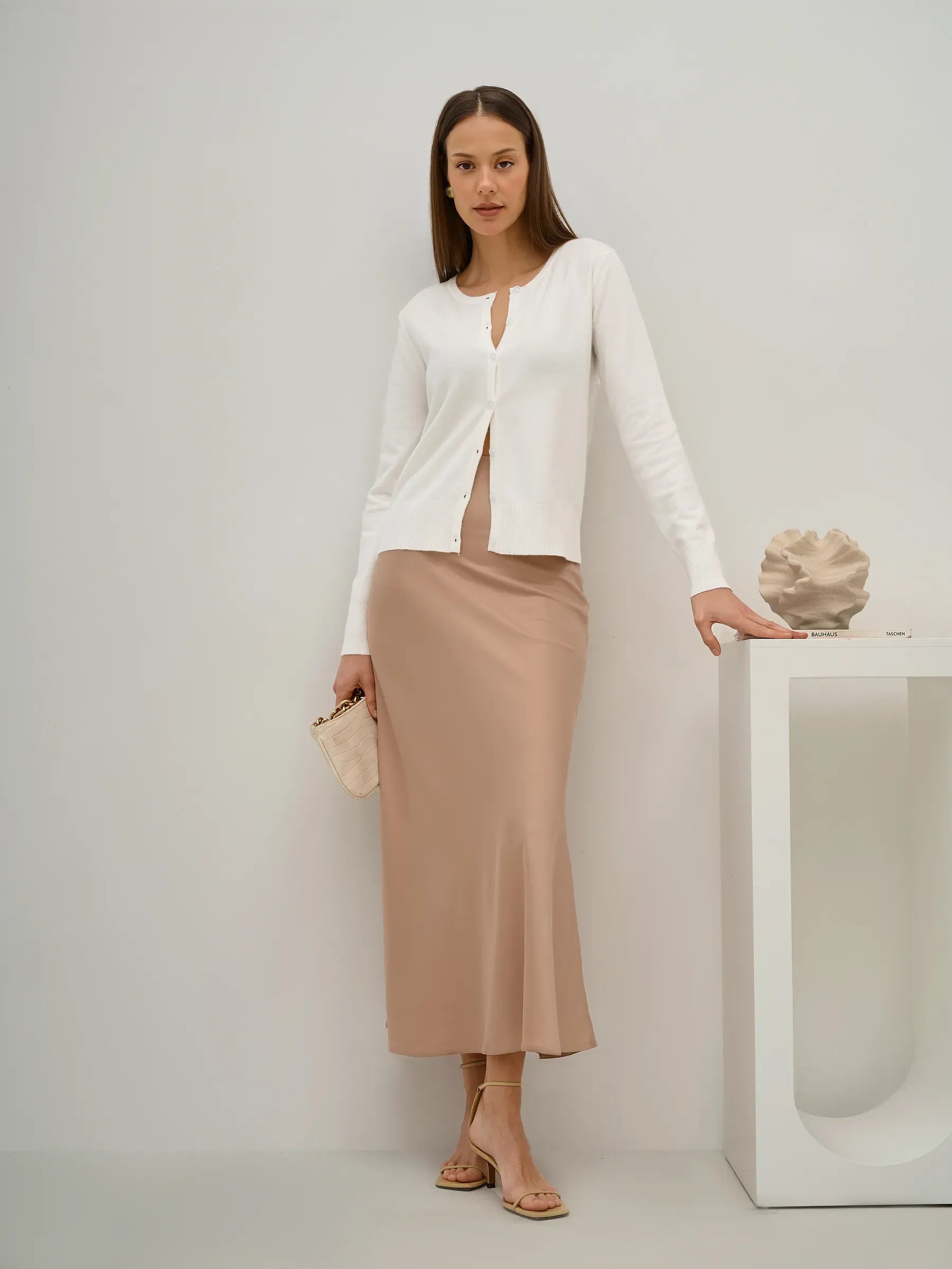Selene Cardigan by Lauven, elegant white knitwear worn with a beige skirt in a stylish setting.