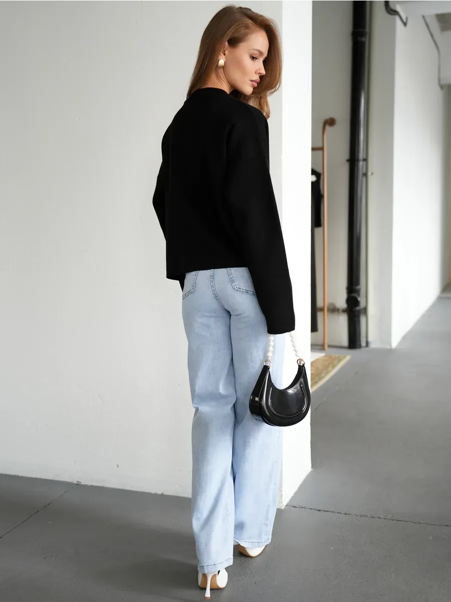 Model wearing the Obsidian Cardigan by Lauven, styled with light blue jeans and a black handbag.