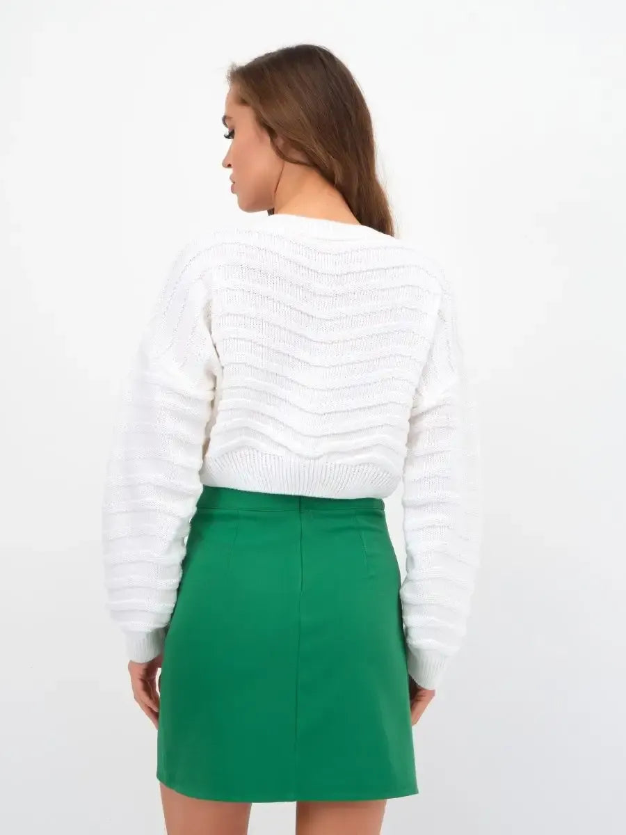 Back view of a woman wearing a white cropped knit Lyra Sweater paired with a green skirt from Lauven.