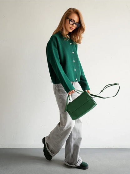 Woman wearing a Verdant Cardigan by Lauven paired with gray jeans and a green handbag.