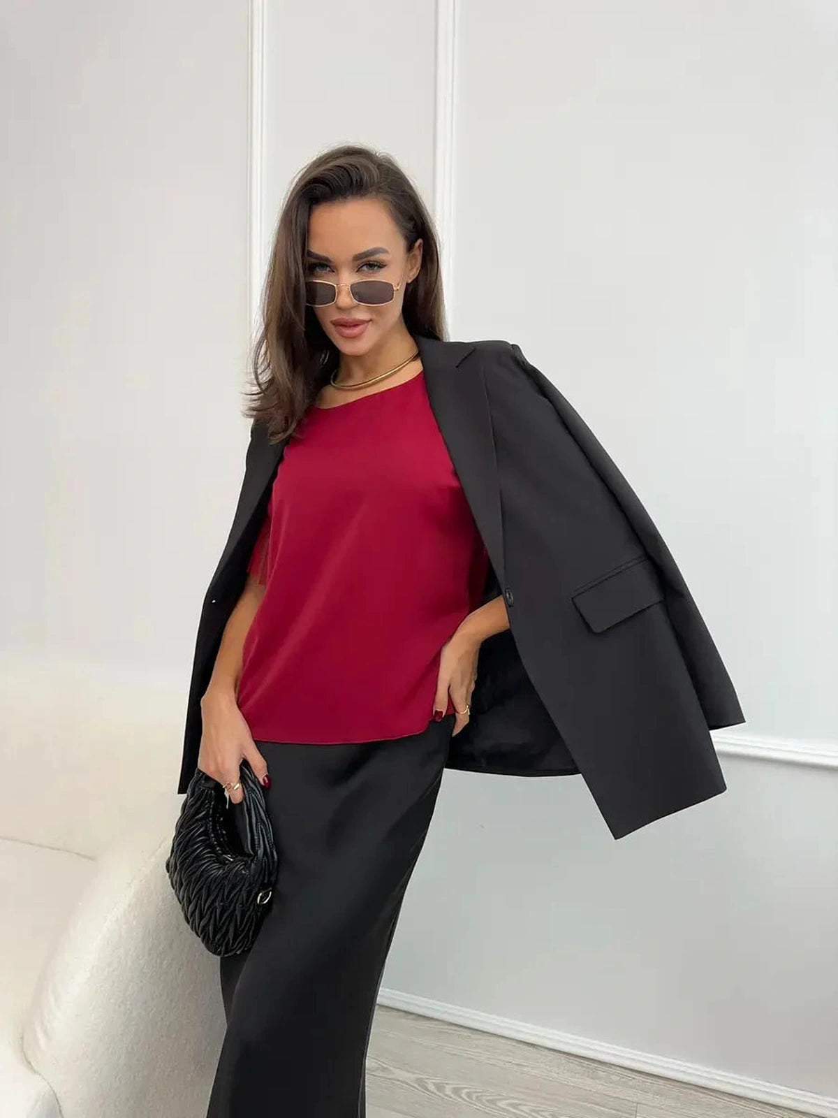 Model wearing Velora Blouse in burgundy with sheer ruffle sleeves, styled with a black blazer from Lauven.