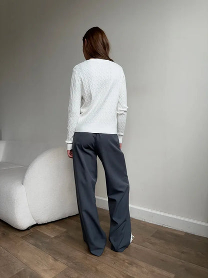 Model wearing an Ivory Cardigan from Lauven, showcasing the back view with grey pants in a modern interior setting.