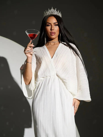 Elegant Selene Midi Dress by Lauven, featuring a flowing silhouette and pleated fabric, worn by a model holding a cocktail.