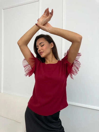 Velora Blouse by Lauven, burgundy short sleeve blouse with sheer ruffle sleeves modeled by a woman.