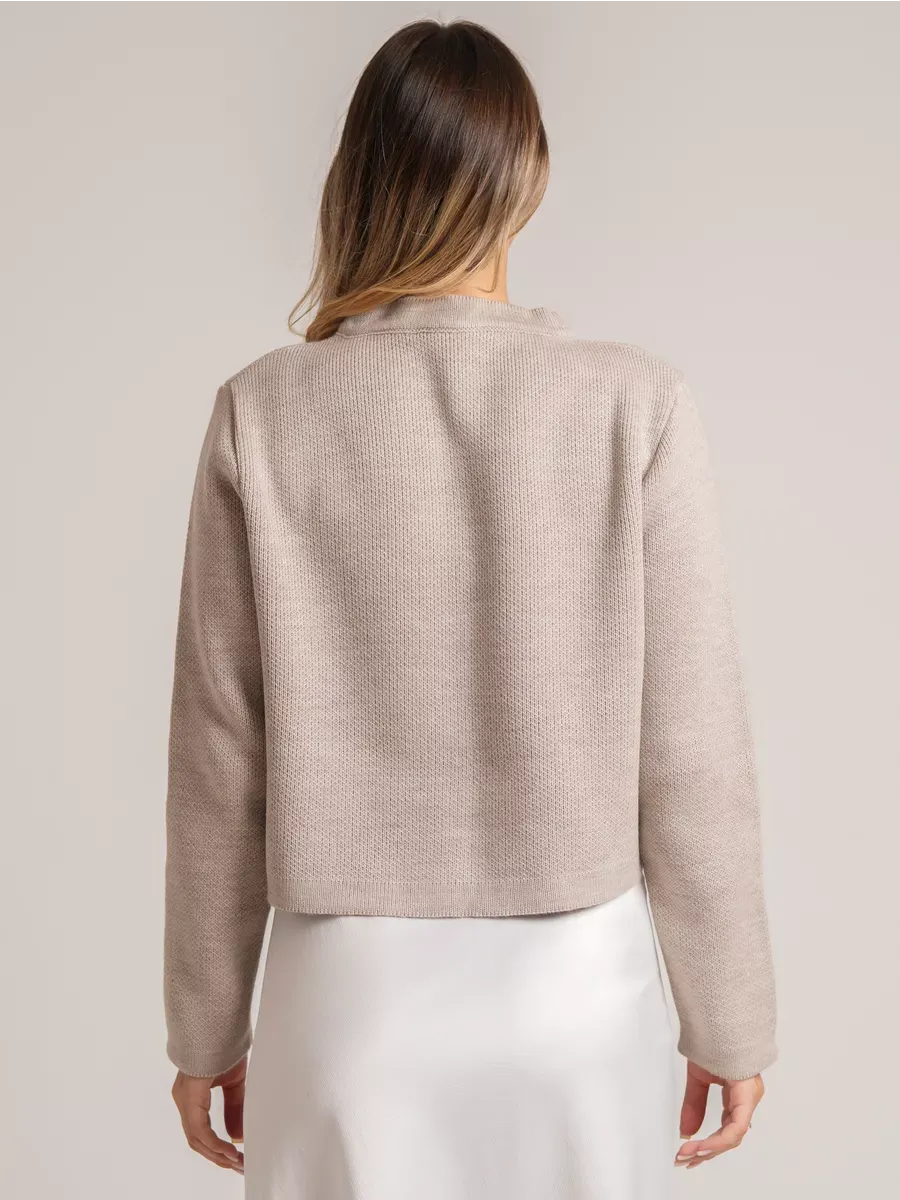 Back view of the Alba Cardigan by Lauven, a beige short loose fit knit with decorative buttons.
