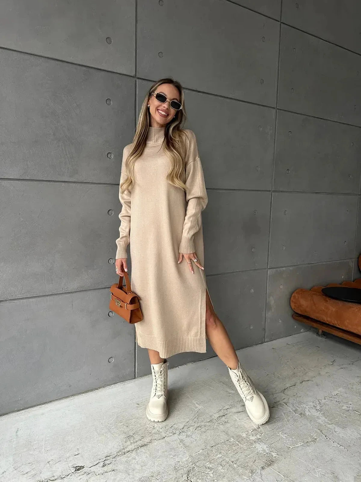 Seren Midi Dress by Lauven, showcasing a woman in a beige knit dress with long sleeves and a side slit in a modern setting.